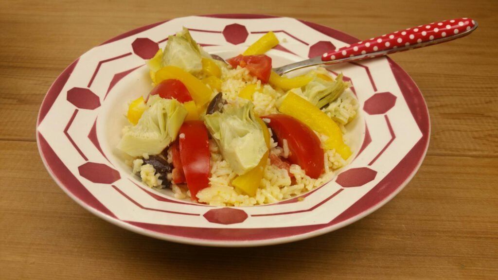 een salade van rijst, met paprika, tomaat en artisjokharten