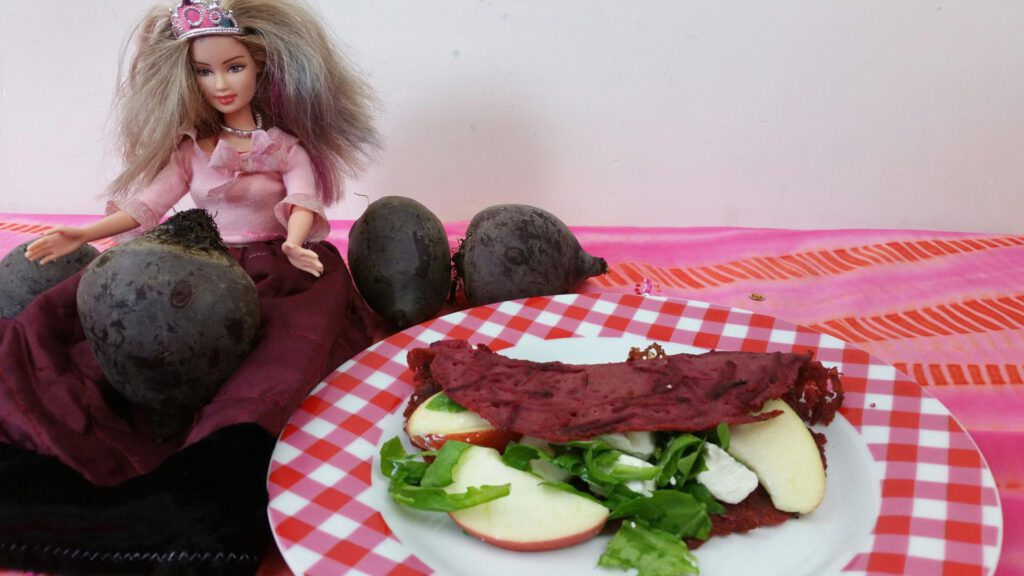 pannenkoek van bietjes, gevukd met ruciola, geitenkaas en appel. Barbie zit er blij naast, blij met zo'n roze pannenkoek