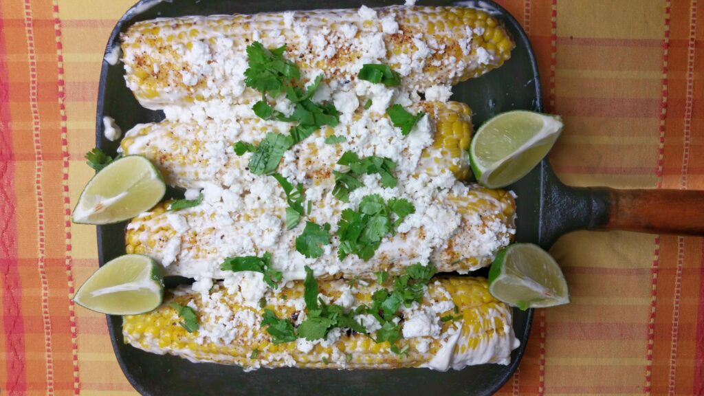 Mexicaanse maiskolven ‘Elotes’, met room, kaas, limoen en koriander