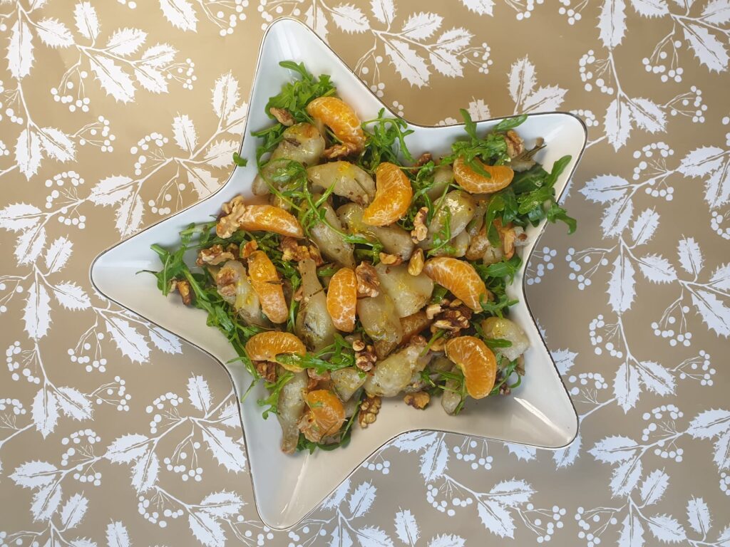 salade in een stervormige schaal met aardpeer, mandarijn, rucola en walnoot