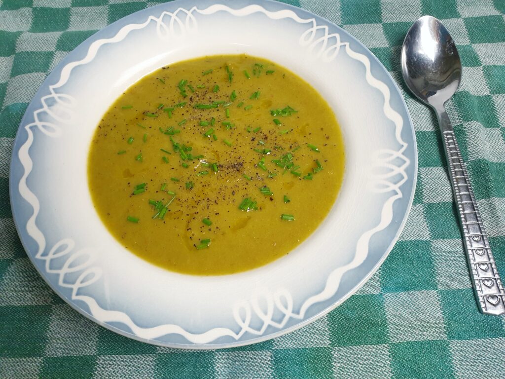 groene soep van prei en wortel, gegarneerd met bieslooksnippers
