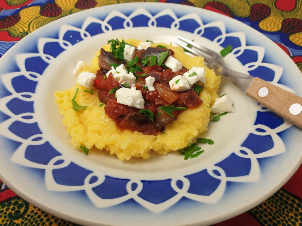 polenta met een saus van aubergine en tomaat, gegarneerd met peterselie en fetablokjes