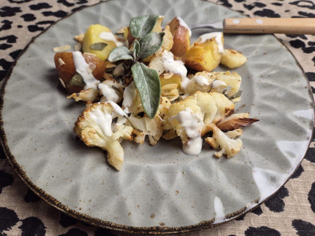 bloemkool en aardappels, geroosterd in de oven met salie en amandelschaafsel, geserveerd met een yoghurtsausje