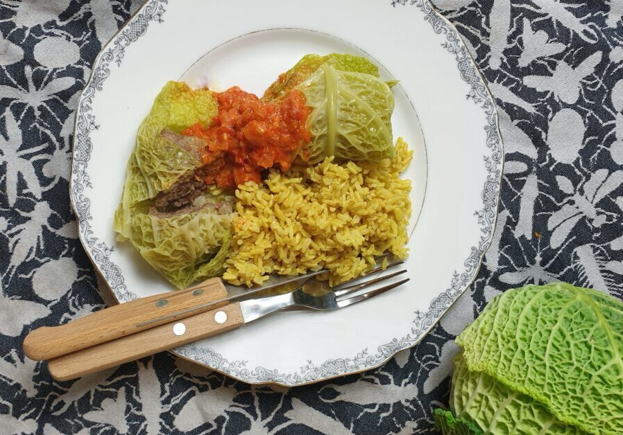 savooiekoolrolletjes gevuld met gehakt. geserveerd met gele rijst en een tomaten-paprikasausje