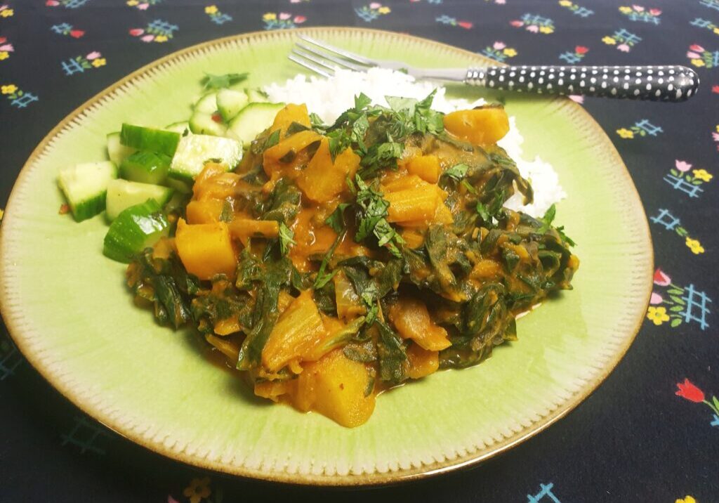 curry van snijbiet, geserveerd met witte rijst en komkommersla
