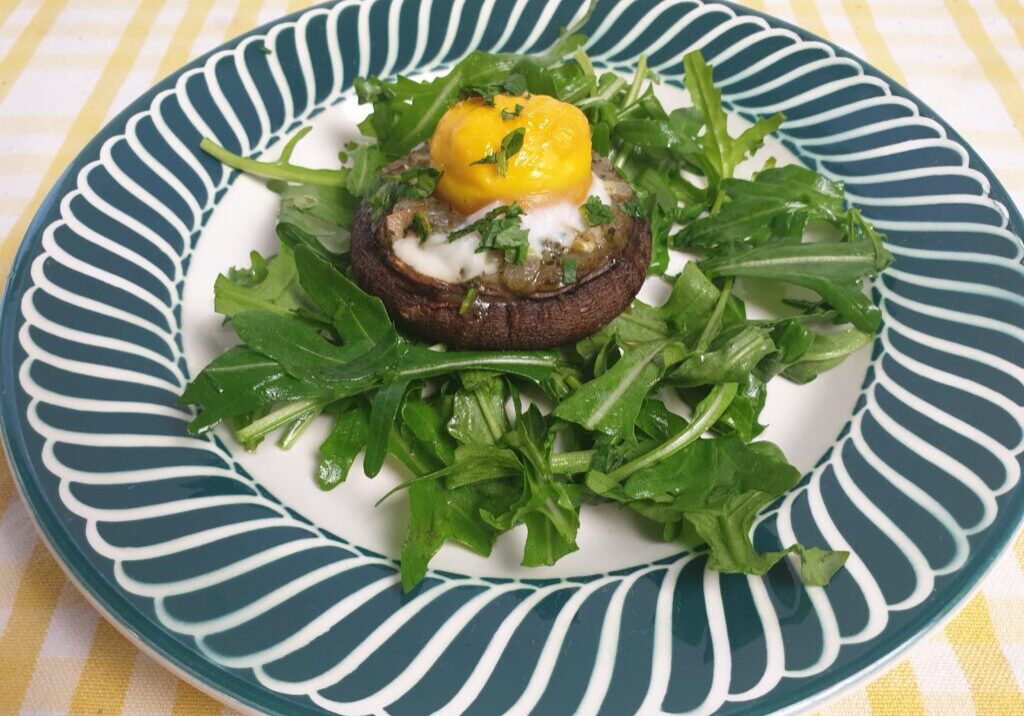 gebakken portobello met eigeel op een bedje van rucola
