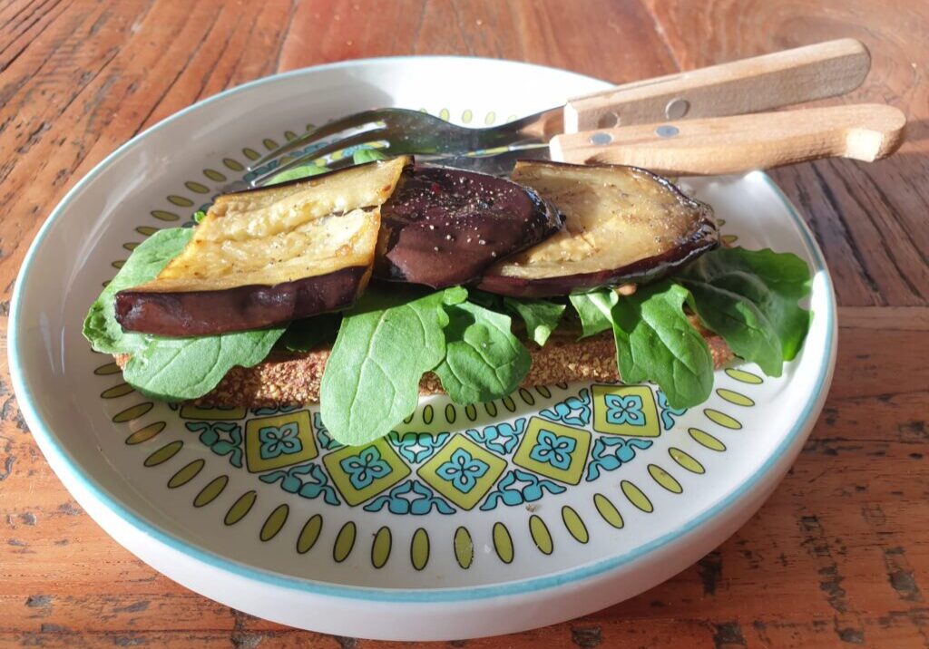 een boterham met tahin, daarop rucola en dan plakjes aubergine
