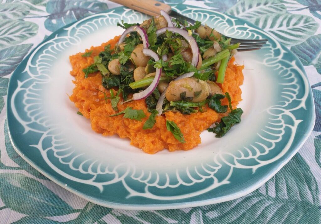 bataatpuree met daarop een mengsel van raapstelen en limabonen, met groene kruiden en rodee ui er over gestrooid
