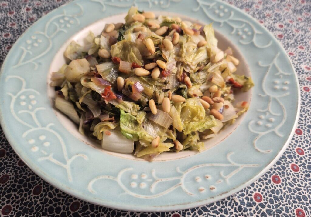 gestoofde groenlof met stukjes tomaat, rozemarijn en geroosterde pijnboompitjes
