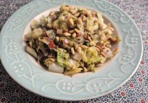 gestoofde groenlof met stukjes tomaat, rozemarijn en geroosterde pijnboompitjes
