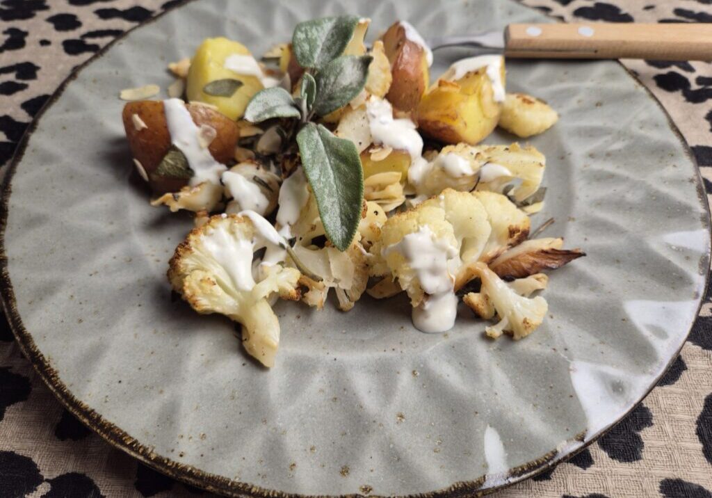 bloemkool en aardappels, geroosterd in de oven met salie en amandelschaafsel, geserveerd met een yoghurtsausje