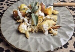 bloemkool en aardappels, geroosterd in de oven met salie en amandelschaafsel, geserveerd met een yoghurtsausje