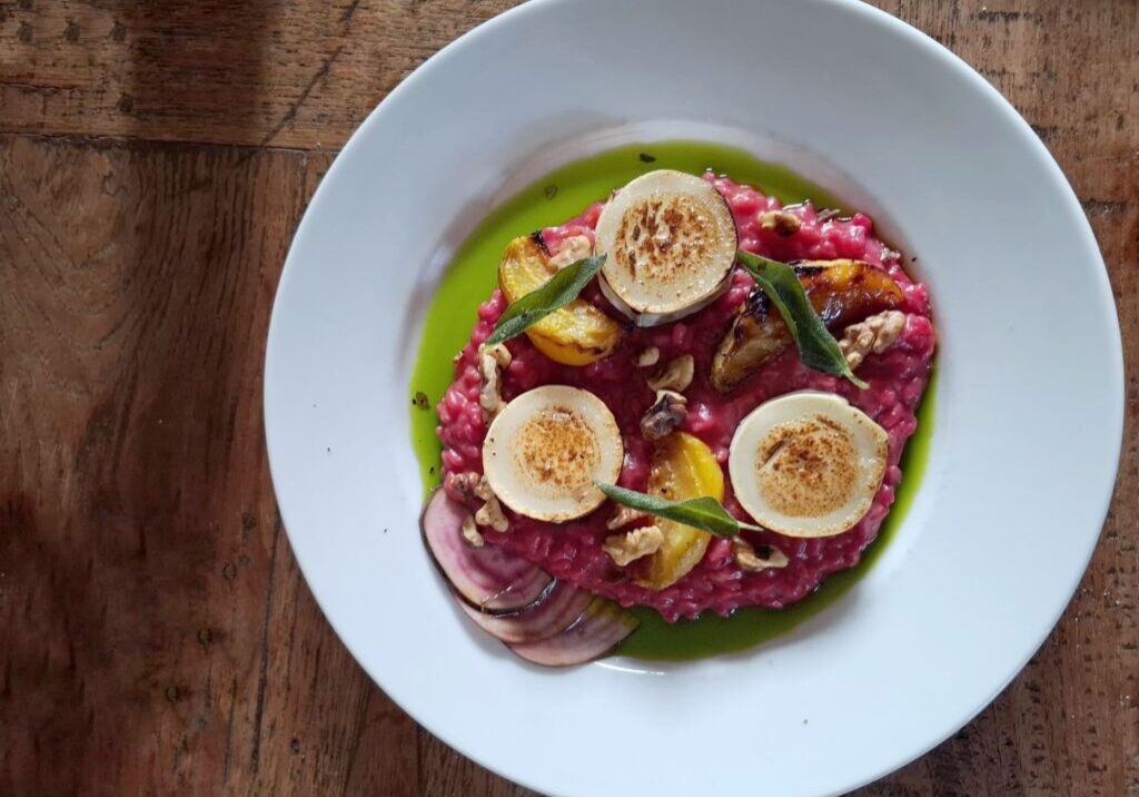 een roze bietenrisotto met gele geroosterde bietjes en gestreepte  gemarineerde chioggabietjes, geitenkaas, salie en walnoten