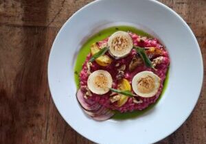 een roze bietenrisotto met gele geroosterde bietjes en gestreepte  gemarineerde chioggabietjes, geitenkaas, salie en walnoten
