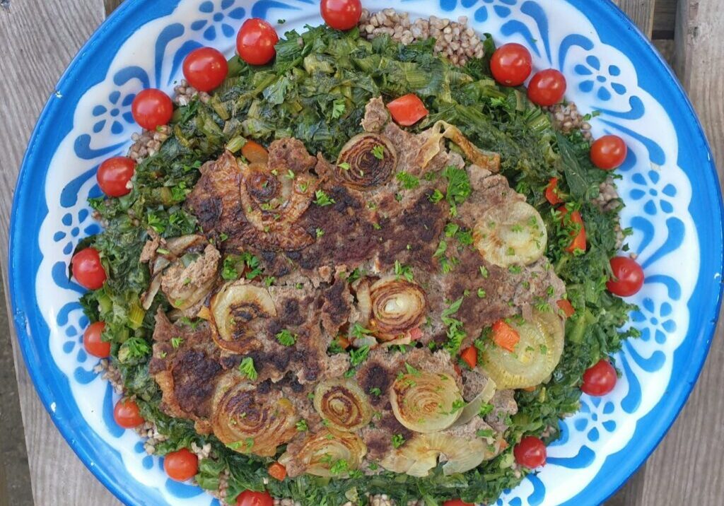 een vrolijke andijvie schotel met gehakt en boekweit, versierd met tomaatjes
