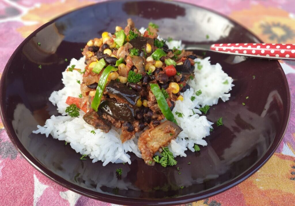 stoof van aubergine, bonen en mais, geserveerd op witte rijst