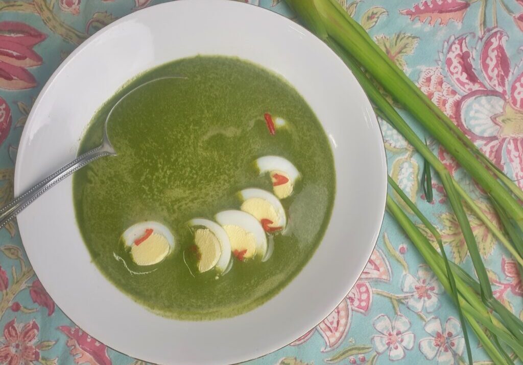 groene spinaziesoep met ei-plakjes en rode peper