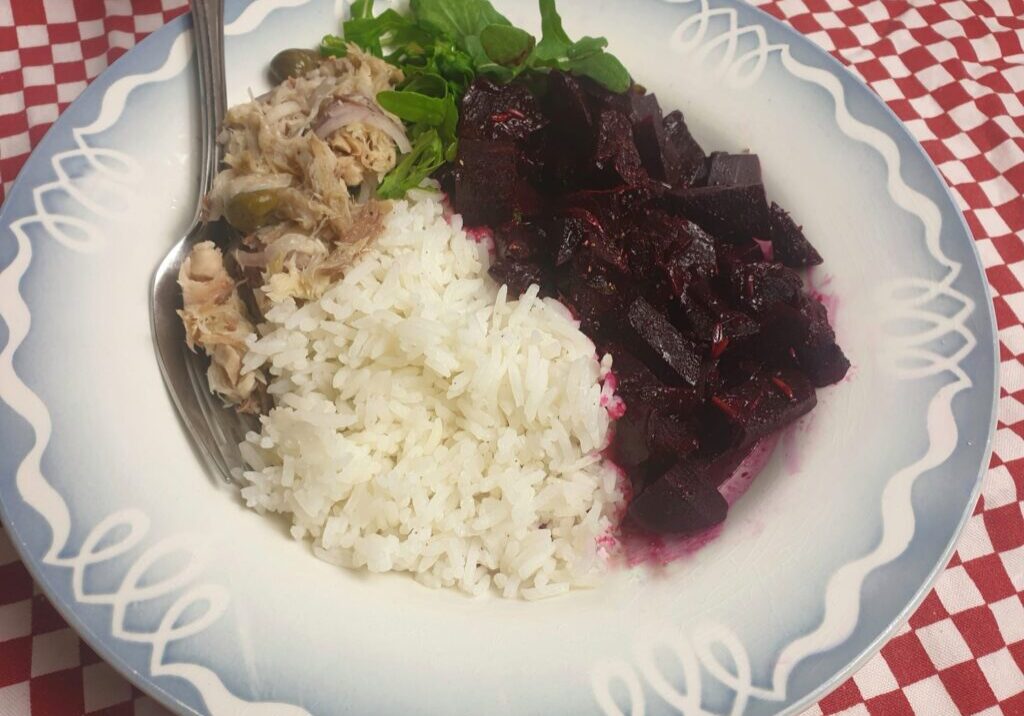 een bord met rode biet, rucola, rijst en makreelsalade
