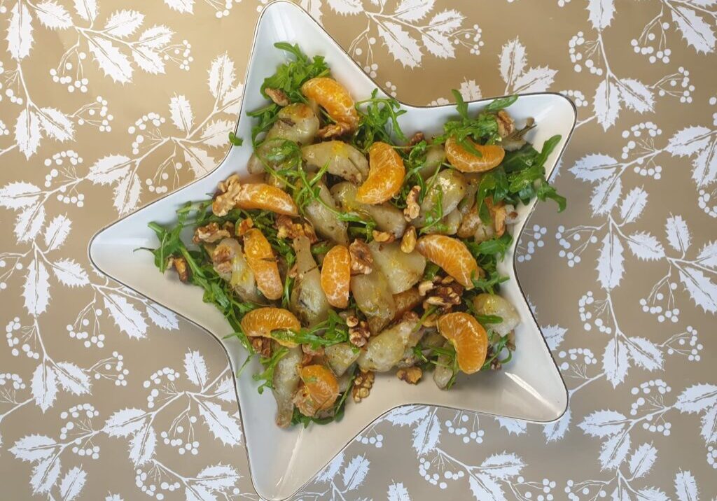salade in een stervormige schaal met aardpeer, mandarijn, rucola en walnoot